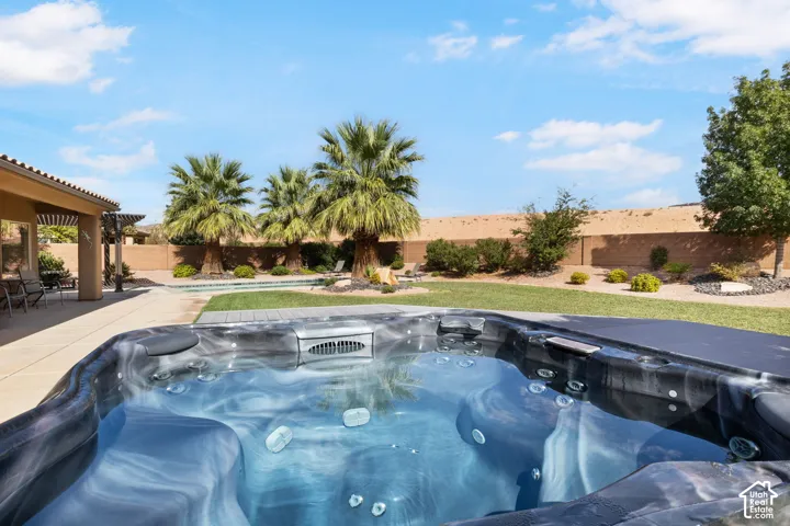 Integrated spa with a textured finish, expansive patio, swimming pool, and mature palm trees