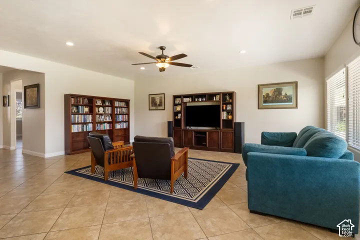 Recessed lighting, ceiling fan, built-in media console, wood-finish shelving, and tile flooring
