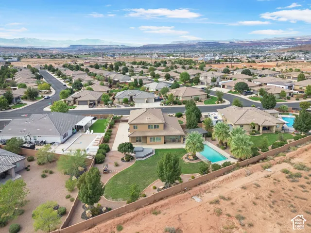 Expansive property featuring a large inground pool, a spacious green lawn, mature palm trees, and a private hot tub