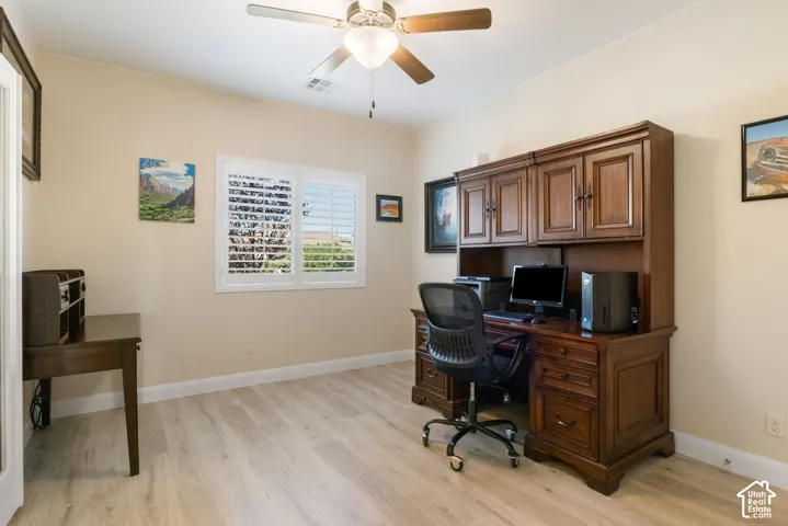 Light wood-finish flooring, white plantation shutters, and a ceiling fan with integrated lighting