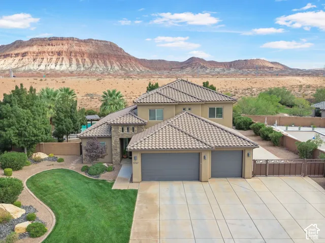 Two-story stucco exterior with stone accents, a multi-car garage, and a tiled roof