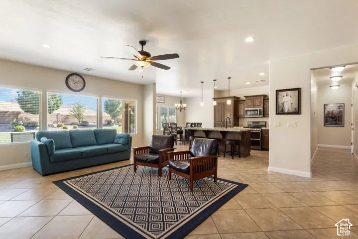 Open-concept living area featuring large windows, neutral-toned tile flooring, recessed lighting, and a ceiling fan