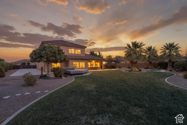Two-story residence with a tile roof, an expansive lawn, and mature palm trees