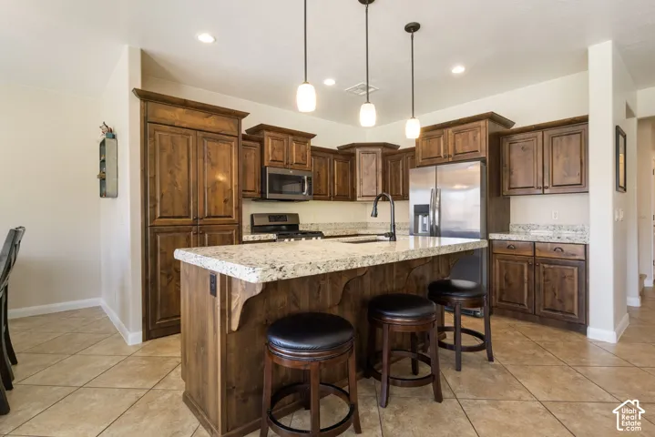 Kitchen featuring wood cabinetry, light-toned countertops, recessed lighting, and a kitchen island with pendant lighting