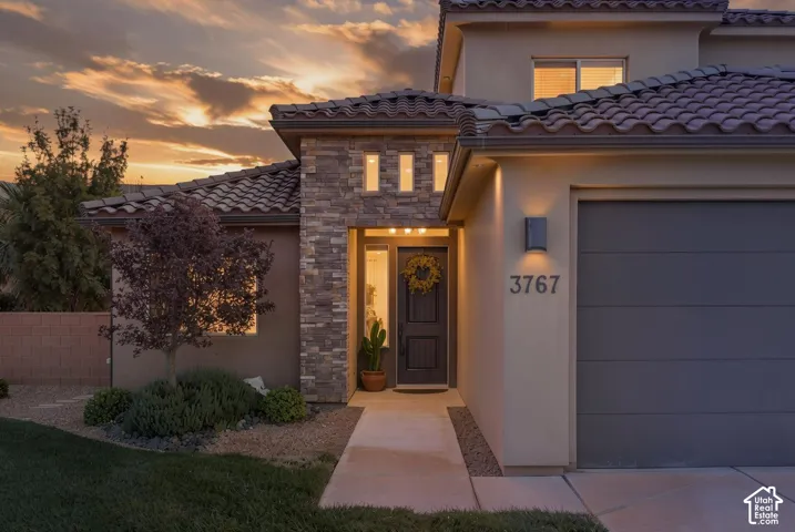 Stucco exterior with stone accents, tile roof, and an attached garage