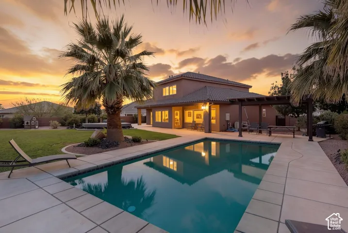 Expansive backyard featuring a rectangular swimming pool, concrete patio, a covered pergola, and mature landscaping