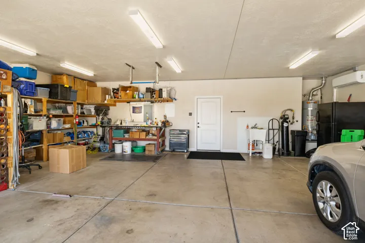 Concrete flooring with overhead strip lighting, white utility door, and built-in shelving units