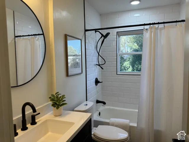 Modern bathroom featuring a vanity with an integrated sink and matte black faucet, a built-in bathtub, and white subway tile surround