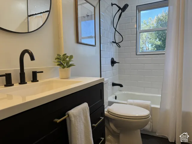 Bathroom featuring a white subway tile shower surround, window with black trim, black vanity with white countertop, and matte black fixtures