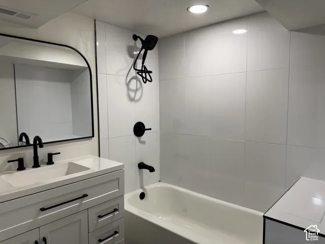 Bathroom featuring a white vanity with a built-in sink, black fixtures, and a rectangular mirror