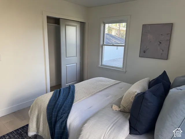 White walls with light wood-finish flooring, a double-paned window, and a sliding closet door