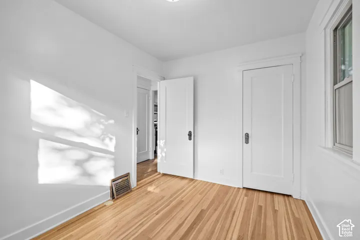 Hardwood flooring, white painted walls, white trim, white panel doors, and a window with white trim