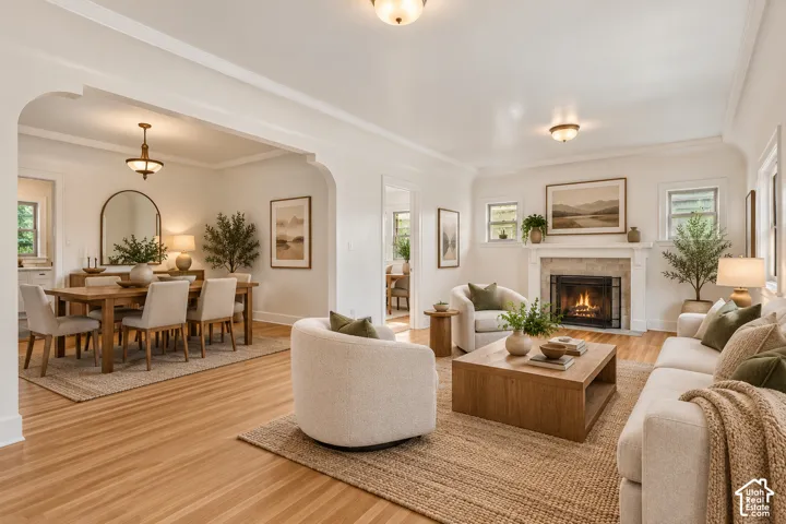 Living area featuring hardwood flooring, arched architectural detailing, and a fireplace with a traditional mantel and stone-tile surround