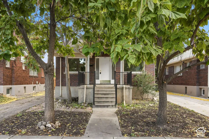 Brick exterior with a covered porch, concrete steps, and black metal railings