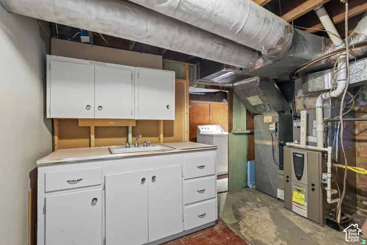 Utility area featuring a sink, white cabinetry, and exposed ductwork