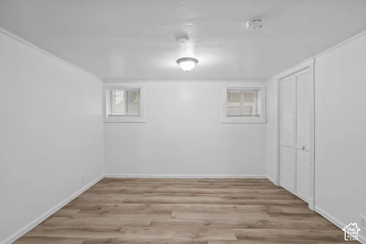 Wood-finish flooring, white walls, two windows, bi-fold louvered closet doors, and an overhead light fixture