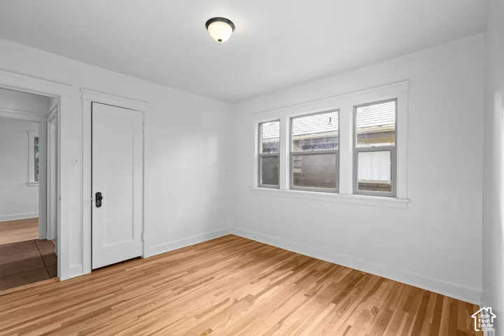 Light-toned wood-finish flooring, white painted walls, and a multi-pane window