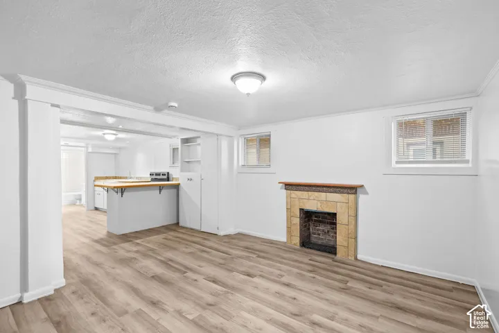 Wood-finish flooring, a stone-surround fireplace with a wood mantle, white walls, and built-in shelving