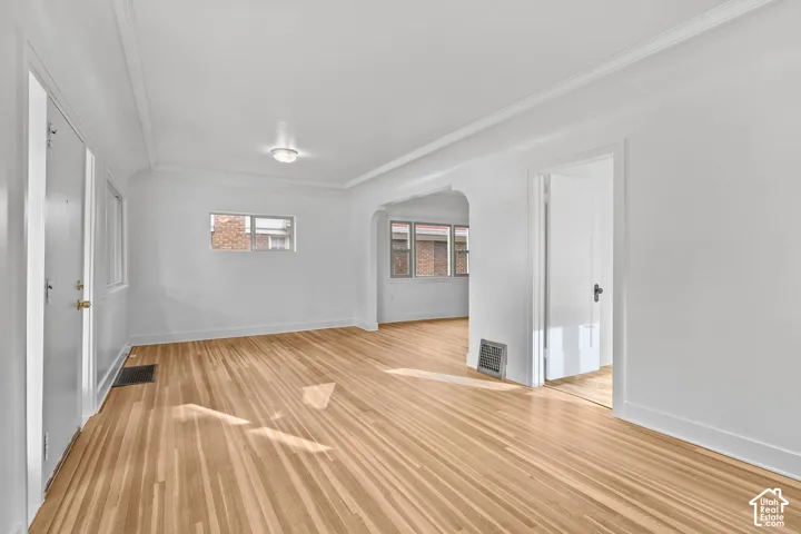 Hardwood flooring, white walls, arched doorway, permanent overhead lighting, and white trim