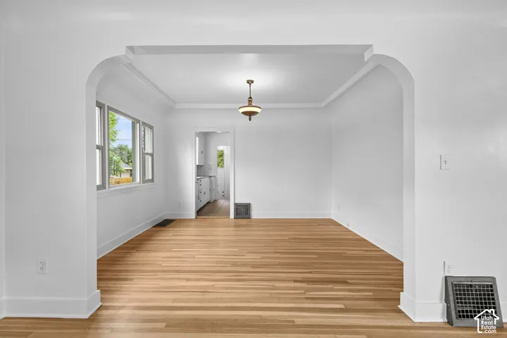 Archway entry with wood-finish flooring, white walls, and a ceiling-mounted light fixture