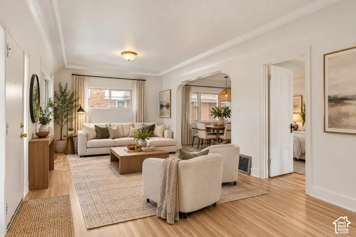 Living area featuring wood-finish flooring, coved ceilings, and a distinctive arched architectural opening