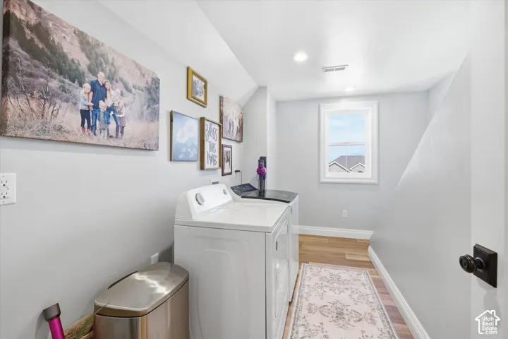 Recessed lighting illuminates the space, featuring light wood-finish flooring and a white-framed window