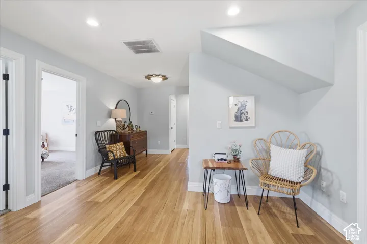Bright and airy upper-level space featuring warm wood-finish flooring throughout, recessed ceiling lighting, and multiple white painted doors