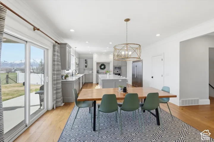 Open-concept kitchen and dining area featuring wood-finish flooring, recessed lighting, and a decorative chandelier