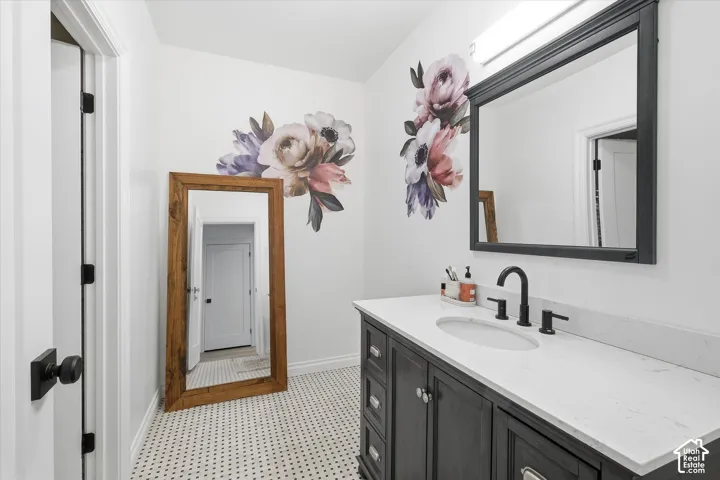 Spa-inspired primary bathroom featuring a charcoal gray vanity with white quartz countertop, matte black faucet fixtures, and an oversized framed mirror