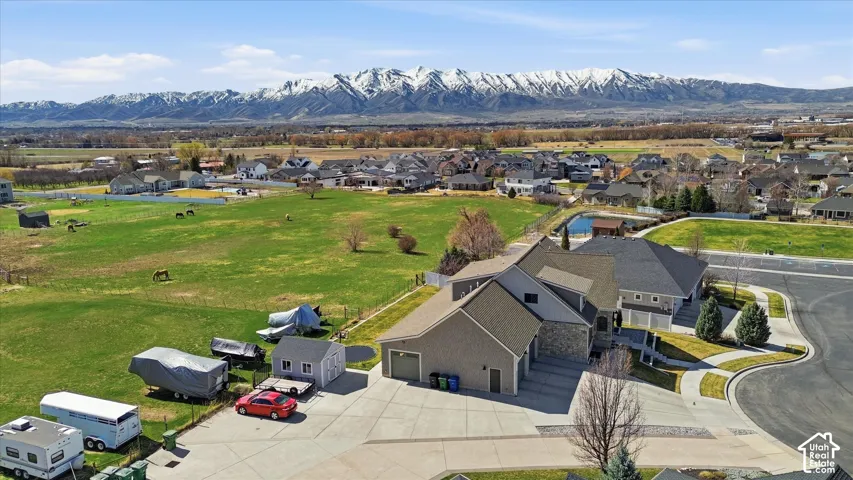 Property situated on a cul-de-sac with an expansive green field, a paved driveway, and multiple garage doors