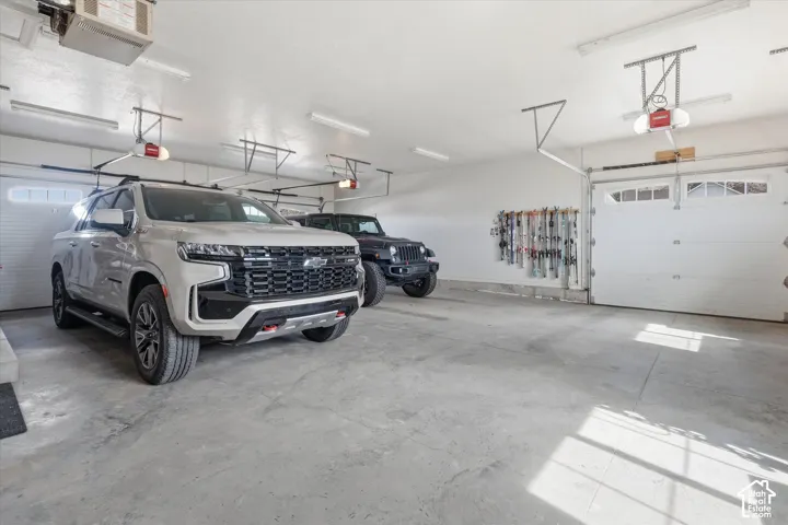 Spacious two-car garage with concrete flooring, multiple overhead lighting fixtures, and two overhead garage doors