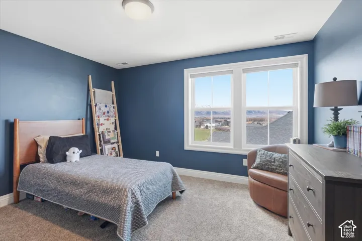 Carpeted room with a flush mount ceiling light fixture, blue painted walls, and a large window featuring white trim