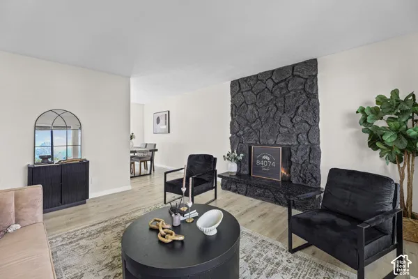 Stone-clad fireplace with a hearth, light wood-finish flooring, and white wall finishes