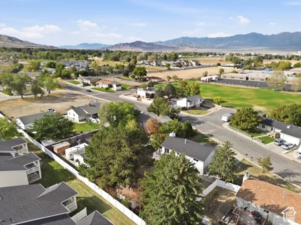 Aerial overview of a residential neighborhood with surrounding mountains, green spaces, and mature trees