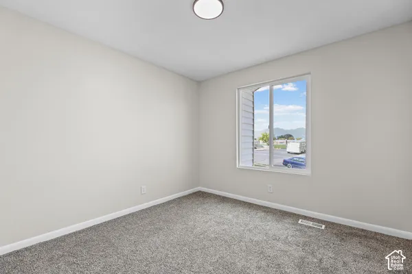 Neutral-toned walls, grey carpet, and a large window with natural lighting
