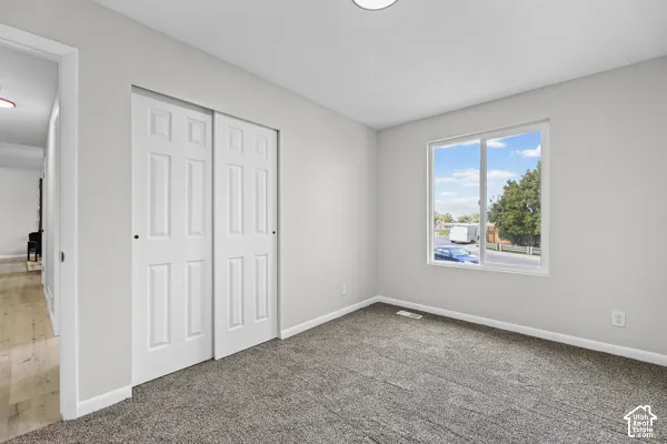 Neutral wall tones, gray carpeting, and a window with a neighborhood perspective
