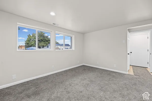 Recessed ceiling lighting, light gray wall paint, gray carpet flooring, white trim, and multiple windows