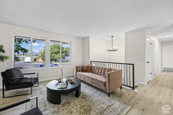 Multiple large windows, wood-finish flooring, white walls, and a black metal stair railing