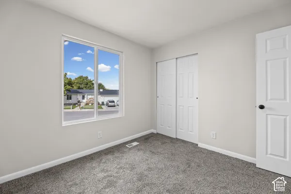 Neutral wall color, carpeted flooring, white trim, sliding closet doors, and white interior door with black hardware