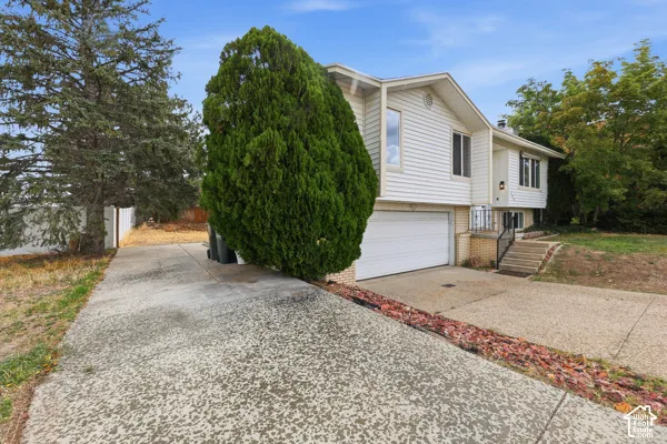 Split-level exterior with white siding, an integrated garage, and a concrete driveway
