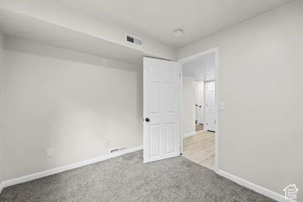 Light gray wall paint, gray carpet flooring, white trim, and a white paneled door with a black handle