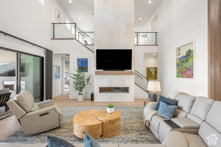 Two-story living area featuring a stone-clad fireplace with a wood mantel, glass sliding doors, and wood-finish flooring