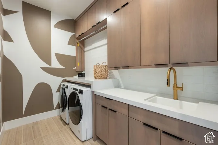 Light wood-finish cabinetry with black hardware, white countertop with integrated sink, brass-finish faucet, and white subway tile backsplash
