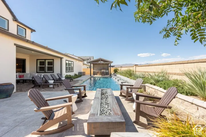 Patio with integrated fire pit, expansive swimming pool, and a covered outdoor kitchen