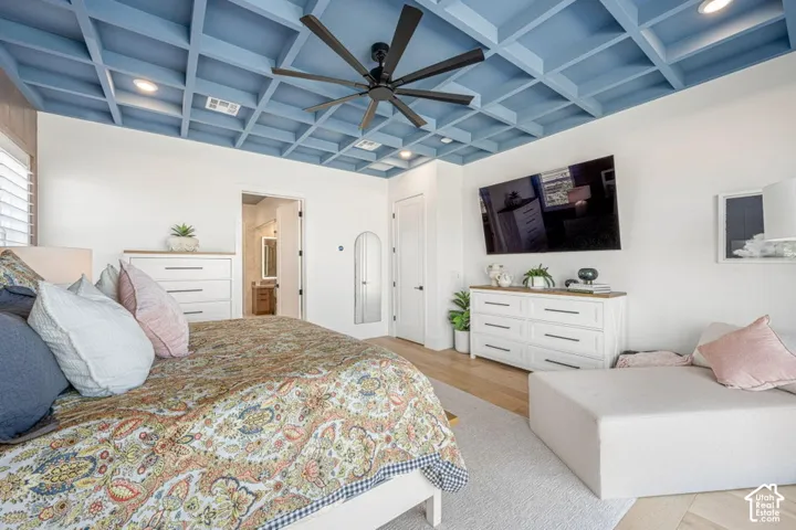 Light blue coffered ceiling with a black ceiling fan, wood-finish flooring, and white interior doors