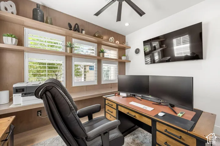 Wood-finish wall paneling, built-in shelving, white plantation shutters, ceiling fan, and recessed lighting