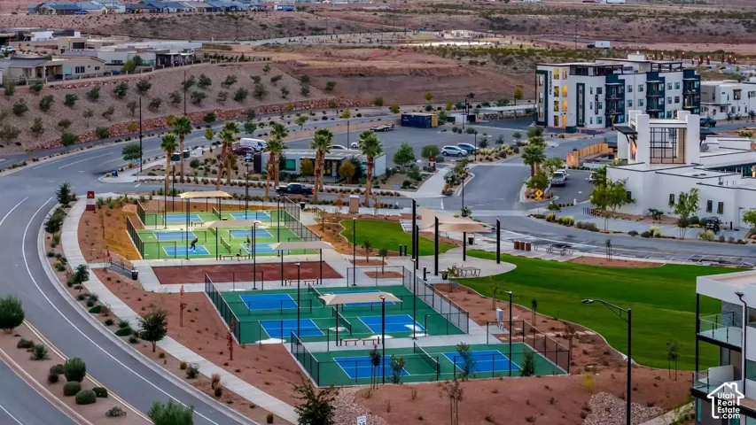Multiple outdoor courts, manicured green spaces, paved pathways, and surrounding residential structures
