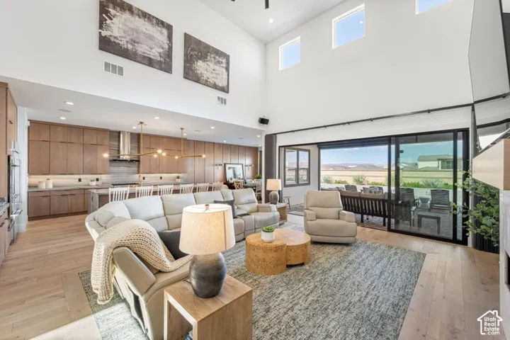 Vaulted ceilings with clerestory windows, wood-finish flooring, a wall of glass sliding doors, recessed lighting, and a kitchen featuring wood cabinetry and a stainless steel range hood
