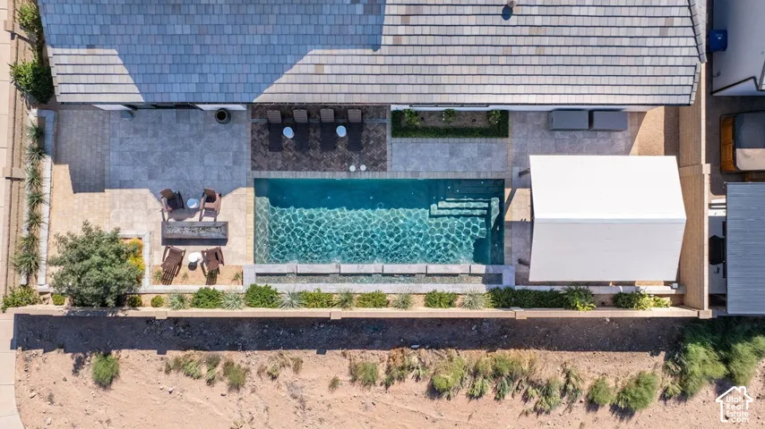 Rectangular swimming pool with integrated steps, surrounded by stone paver patio