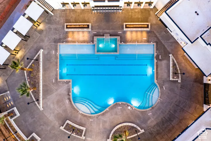 Resort-style aquatic area featuring a large swimming pool, integrated hot tub, and concrete decking